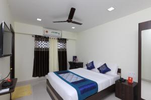 a bedroom with a bed and a flat screen tv at Super Hotel O Perfect Stay Near Meenambakkam Metro Station in Chennai