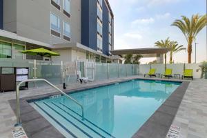 a swimming pool with chairs and a building at SpringHill Suites by Marriott Anaheim Placentia Fullerton in Placentia
