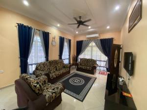 een woonkamer met banken en een plafondventilator bij Idaman homestay in Bukit Mertajam