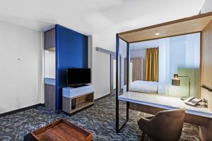 um quarto de hotel com uma secretária, uma cama e uma televisão em SpringHill Suites by Marriott Tulsa at Tulsa Hills em Tulsa