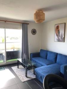 a living room with a blue couch and a table at Les clés du sud sauvage in Saint-Joseph