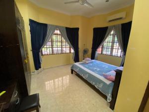 a bedroom with a bed and two windows at Idaman homestay in Bukit Mertajam