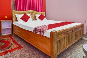 ein Schlafzimmer mit einem großen Holzbett mit roten Kissen in der Unterkunft OYO Flagship Hotel Kashyap Heritage in Patna