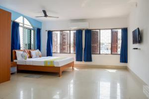 a bedroom with a bed with blue curtains and windows at OYO Home Elite Stay Near Shri Shri Shiridi Sai Mandir in Khandagiri