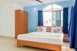 a bedroom with a bed with blue walls and a window at OYO Home Elite Stay Near Shri Shri Shiridi Sai Mandir in Khandagiri