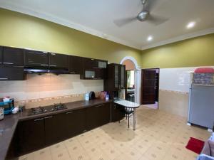 a kitchen with black cabinets and a table in it at Idaman homestay in Bukit Mertajam