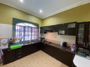 une grande cuisine avec des armoires noires et une fenêtre dans l'établissement Idaman homestay, à Bukit Mertajam