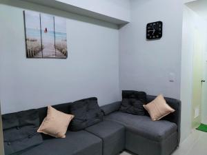 - un salon avec un canapé gris et 2 oreillers dans l'établissement JAZZ DREAM CONDOTEL WITH BALCONY AND SWIMMING POOL, à Manille
