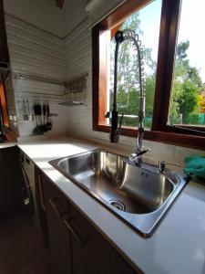 um lavatório de aço inoxidável numa cozinha com uma janela em CASA AZUL LIMAY VILLA LA ANGOSTURA em Villa La Angostura