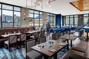 a restaurant with tables and chairs and windows at The Oaklander Hotel, Autograph Collection in Pittsburgh