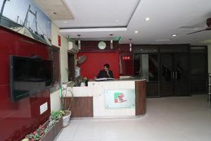 Muthiganj的住宿－Capital O Hotel R Inn，一个人站在大楼的柜台上