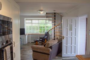 a living room with a couch and a stair case at Grapevine Getaway in Lincolnshire