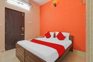 a bedroom with orange walls and a bed with red pillows at Highways Residency in Madurai