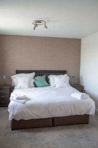 ein Schlafzimmer mit einem großen Bett mit weißer Bettwäsche und Kissen in der Unterkunft Grapevine Getaway in Lincolnshire