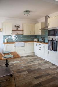 a kitchen with white cabinets and a wooden floor at Grapevine Getaway in Lincolnshire