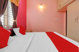 a bedroom with a large bed with red and white pillows at Highways Residency in Madurai