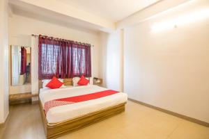 OYO Primrose Regency Near Amanora Mall في Kharadi: غرفة نوم بسرير ومخدات حمراء ونافذة
