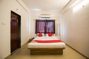 Schlafzimmer mit einem Bett mit roten Kissen und einem Fenster in der Unterkunft OYO Primrose Regency Near Amanora Mall in Kharadi