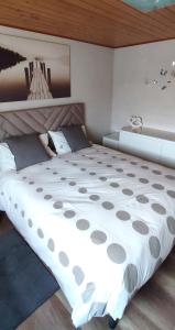 sypialnia z dużym białym łóżkiem i drewnianym sufitem w obiekcie Regina del Bosco della vicina Cavalese w mieście Daiano