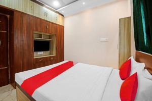 um quarto com uma cama branca e almofadas vermelhas em OYO Pratikshya A1 Residency em Bhubaneshwar