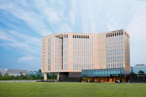 a large office building with a field in front of it at Courtyard by Marriott Seoul Botanic Park in Seoul