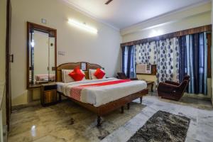 a bedroom with a bed and a mirror and a chair at Hotel Vinayak in Udaipur
