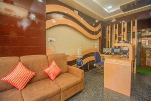 Sofá marrón con 2 almohadas rojas en el vestíbulo en Hotel Stay In en Kuch Bihār