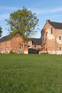 a large brick building with a tree in a field at Chambres de Gilberoux in Floreffe