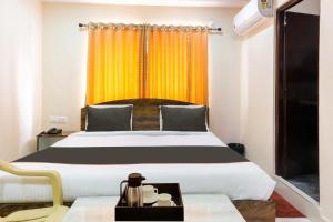 a bedroom with a large bed and a yellow curtain at Capital O Mvp Check Inn in Jalāripeta