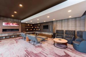 a waiting room with chairs and a table and a tv at Courtyard Louisville Downtown in Louisville