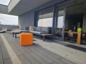 sala de estar con sofá y reposapiés naranja en Exklusives Design-Penthouse MC1, en Seligenstadt