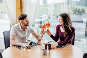 Ein Mann und eine Frau sitzen am Tisch und trinken Champagner. in der Unterkunft Auberge de Jeunesse Saignelégier in Saignelégier