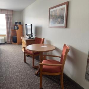 Habitación de hotel con mesa, sillas y escritorio. en Duluth Inn & Suites Near Spirit Mountain en Duluth