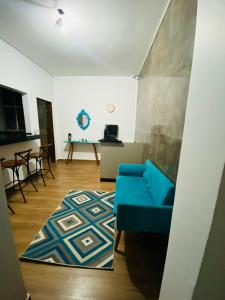 a living room with a blue couch and a rug at Hotel Santorine Plaza - By UP Hotel in Itabira