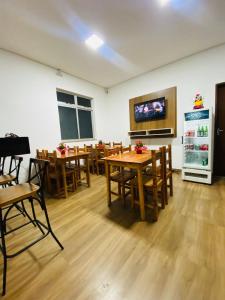 a dining room with wooden tables and a flat screen tv at Hotel Santorine Plaza - By UP Hotel in Itabira