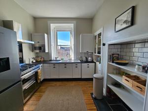 eine Küche mit weißen Schränken und einem großen Fenster in der Unterkunft Garnethill Upper in Glasgow