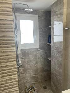 a bathroom with a shower with a window at Airport View Apartments in Artemida