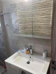ein weißes Waschbecken im Bad mit Spiegel in der Unterkunft Airport View Apartments in Artemida