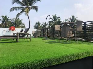 a park with chairs and grass and palm trees at The Plazinn by Legends Hotels in Candolim