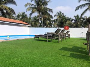 a row of chairs on a lawn next to a swimming pool at The Plazinn by Legends Hotels in Candolim