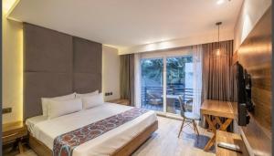 a hotel room with a bed and a desk and a window at The Plazinn by Legends Hotels in Candolim