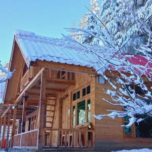 a log cabin with snow on the roof at Himalayan Cedar Nest in Sainj