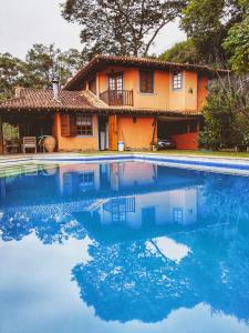 a house and a swimming pool in front of a house at Linda casa em Itaipava in Petrópolis