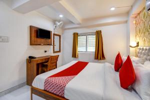 a bedroom with a bed with red pillows and a television at OYO Diamond Plaza Near Acropolis Mall in Jādabpur