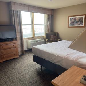 ダルースにあるDuluth Inn & Suites Near Spirit Mountainのベッドとテレビが備わるホテルルームです。