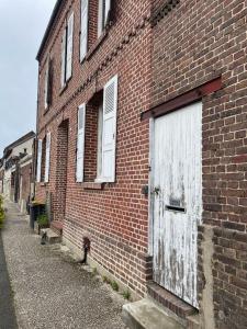 a brick building with a white door on the side of it at Le clos de Marissel in Beauvais