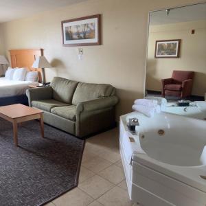 a living room with a couch and a tub in a hotel room at Duluth Inn & Suites Near Spirit Mountain in Duluth