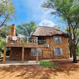 a large brick house with a thatched roof at Bliss in Marloth Park