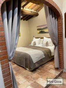 ein Schlafzimmer mit einem Bett in einer Ziegelwand in der Unterkunft PienzaLettings "Casa Gioia" in Pienza