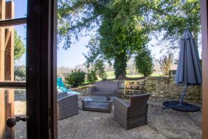 patio z kanapą i parasolem w obiekcie le petit gite Maison Croix du Sud w mieście Saint-Amand-de-Vergt